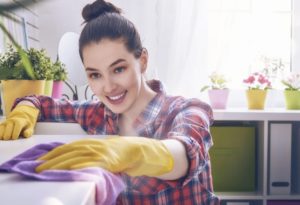 woman in plaid shirt and yellow gloves cleaning a well-lit room